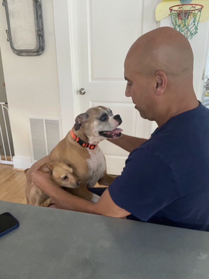 Rachid holding tan dog indoors